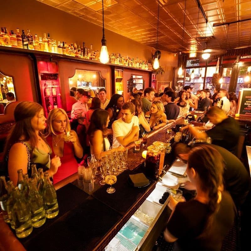 Exposed brick bar room with chandeliers and warm lighting at Velvet Brooklyn in Williamsburg