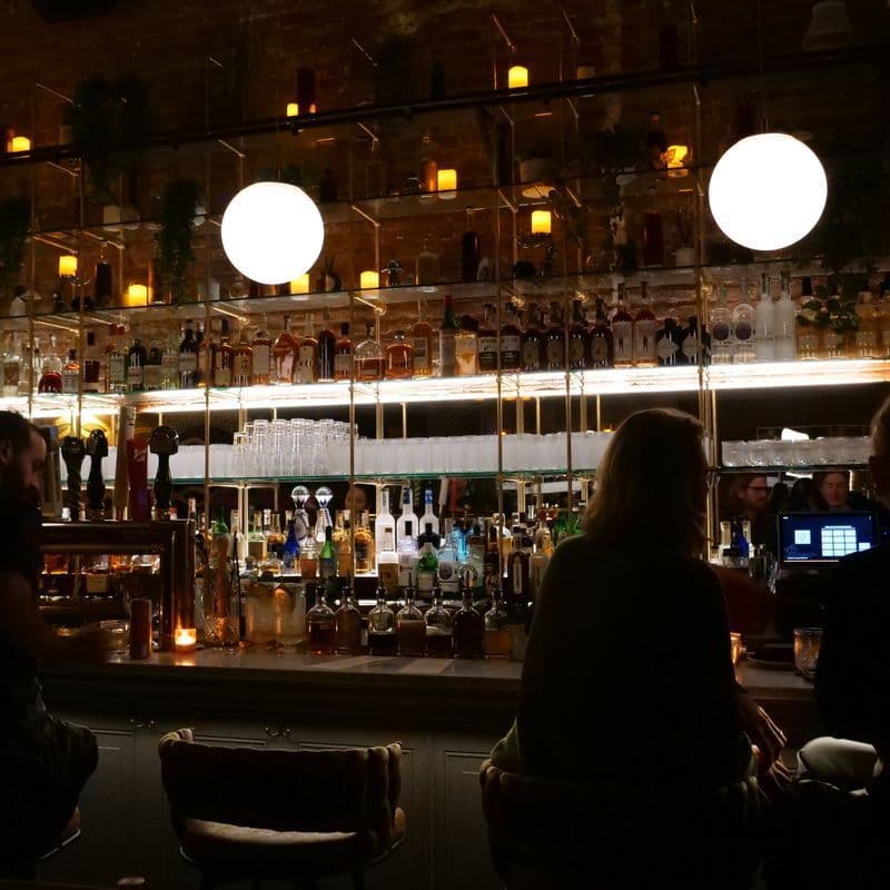 Dimly lit bar interior at Little More in Tribeca with the long marble bar and spirits library