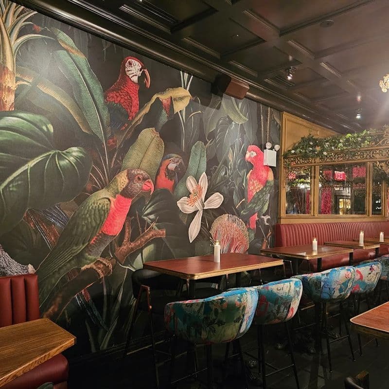 Cocktail lounge interior at Boss Tweeds in Tribeca with red wallpaper, velvet seating, and gold accents