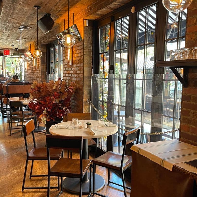 Dining space at LOULOU French bistro in Chelsea with warm lighting and greenery
